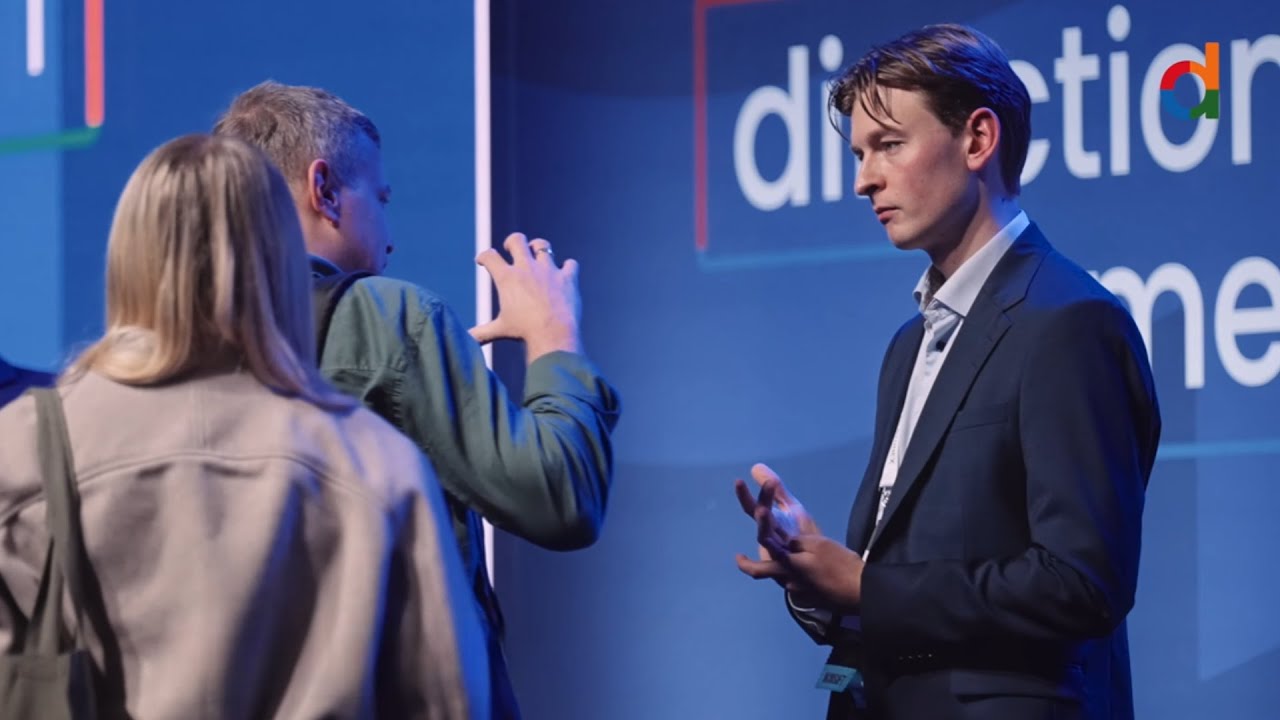 Tres personas conversan frente a un panel azul con la marca Directions en una imagen del resumen oficial de Poznań 2025.