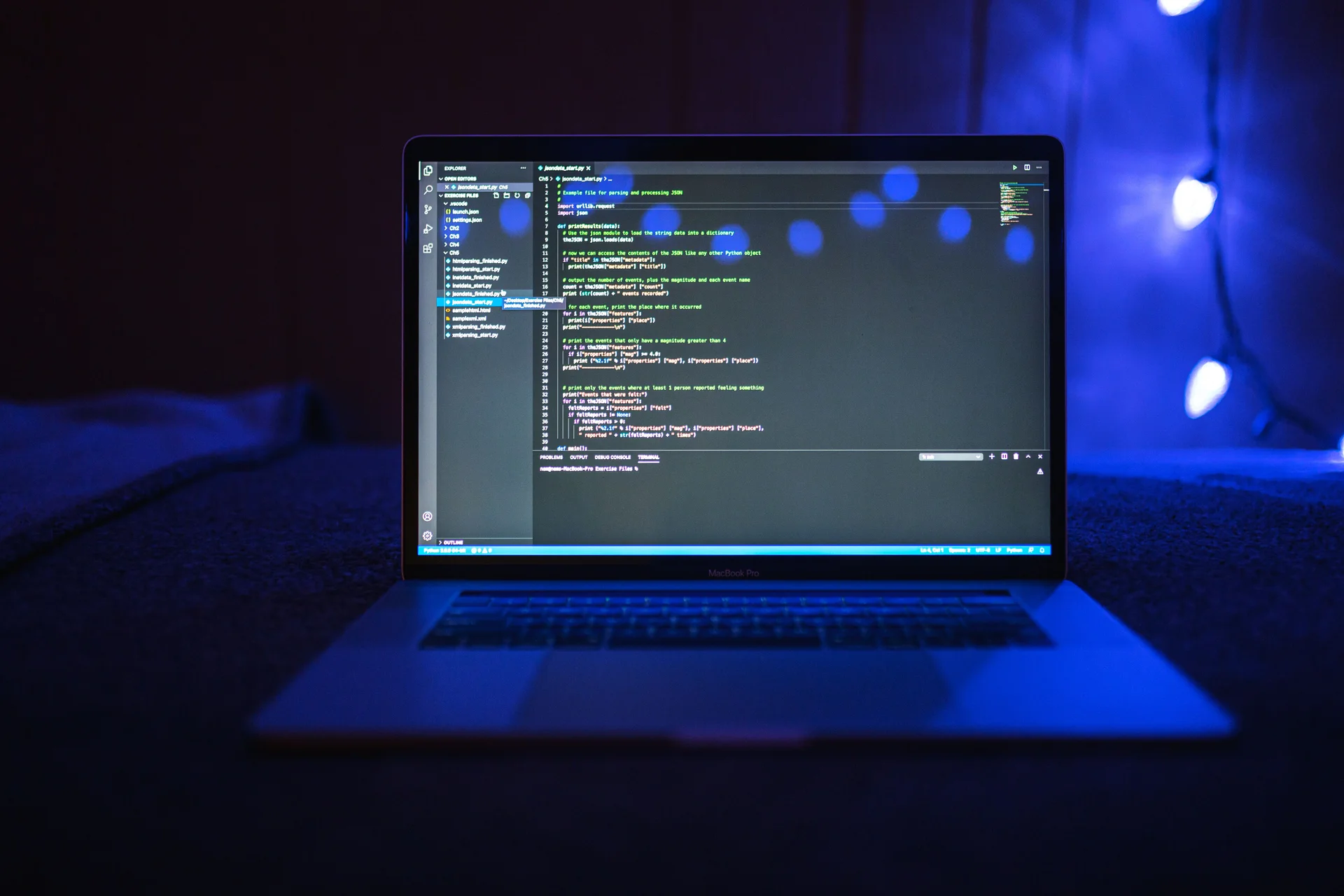 Open laptop displaying a code editor in a dark setting with blue lighting.