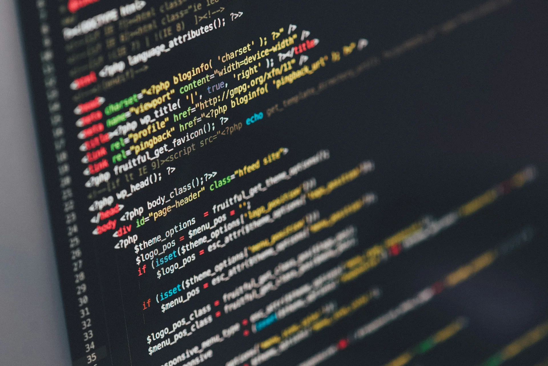 Angled close-up of a screen displaying source code in multiple colors and line numbers against a dark background.